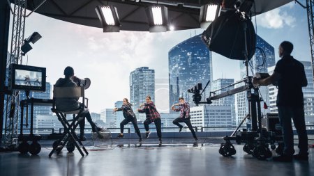 Foto de Conjunto de estudio de clip musical: escena de baile de video de hip hop con tres bailarines profesionales que actúan en el escenario con pantalla led grande con ciudad moderna - Imagen libre de derechos