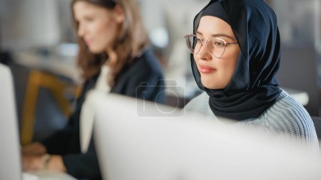 Téléchargez les photos : Beau portrait d'une étudiante musulmane à Hijab, étudiant à l'université. Elle travaille sur ordinateur de bureau à l'université. Appliquer ses connaissances à - en image libre de droit