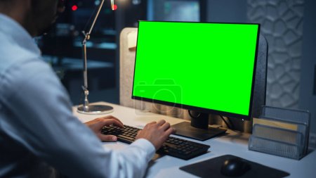 Photo for Close Up of a Businessman Working on Desktop Computer with Chroma Key Green Screen Mock Up Display. Male Executive Director Managing Digital Projects - Royalty Free Image