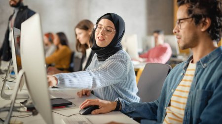 Téléchargez les photos : Étudiante musulmane heureuse portant un hijab, étudiant à l'université moderne avec divers camarades de classe multiethniques. Elle pose une question au chercheur au collège - en image libre de droit
