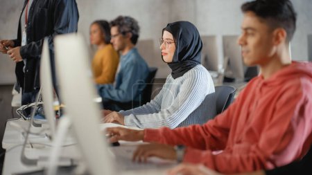Foto de Estudiante musulmana en Hijab, Estudiando en la Universidad. Trabaja en Computadora de Escritorio en la Universidad con Diversos Compañeros Multiétnicos. Aplicándola a ella - Imagen libre de derechos