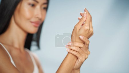 Female Beauty Portrait. Beautiful Asian Happy Brunette Woman Posing, Touching Her Hands with Natural, Healthy Skin. Wellness and Skincare Concept on