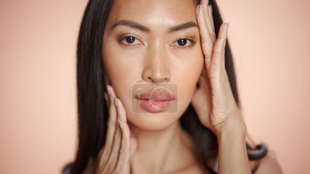 Téléchargez les photos : Portrait de beauté féminine. Belle femme brune asiatique posant, souriant, touchant son visage avec une peau naturelle et saine. Concept Bien-être et Soins de la - en image libre de droit