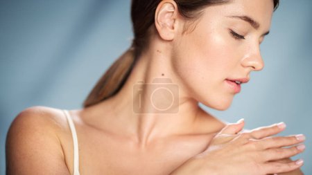Portrait de beauté féminine. Femme caucasienne heureuse aux cheveux bruns Touchant une peau naturelle et saine, utilisant un écran solaire, appliquant une crème nourrissante. Produits cosmétiques