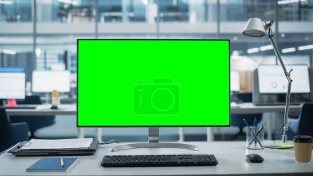 Photo for Desktop Computer Monitor with Mock Up Green Screen Chroma Key Display Standing on the Desk in the Modern Business Office. In the Background Glass Wall - Royalty Free Image
