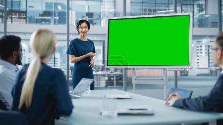 Foto de Mujer Gerente de Operaciones realiza una presentación de la reunión para un equipo de economistas. Mujer asiática utiliza pizarra digital con pantalla verde horizontal Mock - Imagen libre de derechos