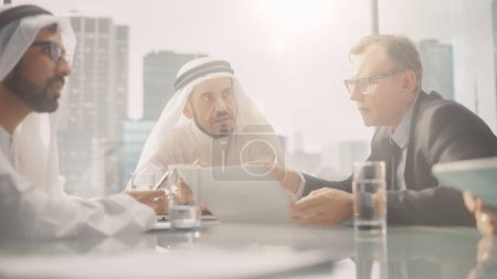 Foto de International Business Consultant Advises on Financial Strategy Plan to Successful Arab Company Owners (en inglés). Encuentro multicultural en la oficina moderna entre - Imagen libre de derechos