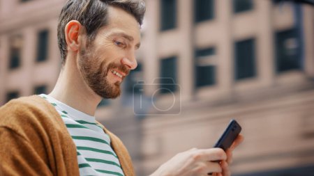 Photo for Street Shot: Portrait of Caucasian Man Using Smartphone in the Big City. Creative Professional Using Mobile Phone App for e-Commerce Online Shopping - Royalty Free Image