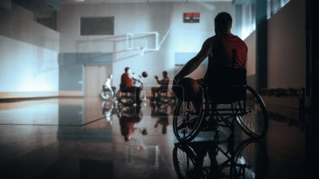 Photo for Wheelchair Basketball Game: Player Wearing Red Shirt Holding Ball Waiting for His Turn. Athlete Watching His Team Play. Concept Shot with Gray Colors - Royalty Free Image