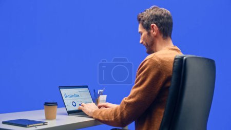 Téléchargez les photos : Écran vert Bureau Contexte : Homme d'affaires caucasien assis à son bureau travaillant sur un ordinateur portable. Homme blanc travaillant avec Big Data e-Commerce - en image libre de droit