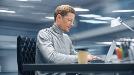 Photo for Modern Office: Productive Businessman Sitting at His Desk Working on a Laptop Computer. Man working with Big Data e-Commerce Analysis. Energetic Shot - Royalty Free Image