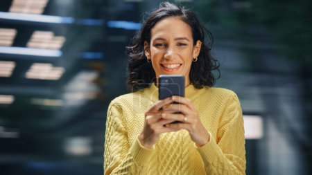 Foto de Street Shot: Retrato de una hermosa mujer latina usando Smartphone. Emprendedora Hispana Sonriente Usando Teléfono Móvil para Compras en Línea, e - Imagen libre de derechos