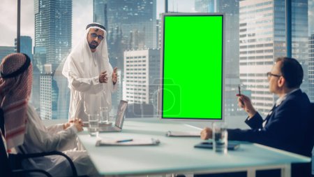 Téléchargez les photos : Saudi Businessman organise une conférence pour les partenaires commerciaux internationaux. Arab Manager utilise un tableau blanc numérique avec un faux écran vert vertical - en image libre de droit