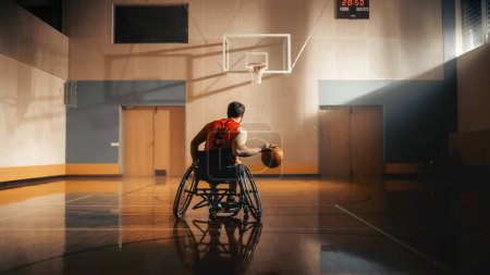 Téléchargez les photos : Wheelchair Basketball Player Dribbling Ball Like a Professional, Ready to Shoot and Score Goal. Determination, Motivation of a Person with Disability - en image libre de droit