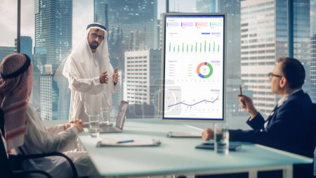 Téléchargez les photos : Emirati Businessman organise une conférence pour les partenaires commerciaux internationaux. Le gestionnaire utilise un tableau blanc avec analyse de la croissance, graphiques, statistiques - en image libre de droit