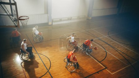 Téléchargez les photos : Terrain de jeu de basketball en fauteuil roulant : Joueurs professionnels paraplégiques concourant, passant, tirant la balle. Détermination, inspiration et compétence d'un peuple - en image libre de droit
