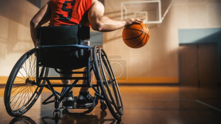 Téléchargez les photos : Joueur de basketball en fauteuil roulant portant une chemise rouge Dribbling Ball comme un professionnel. Détermination, motivation d'une personne handicapée Excellant à - en image libre de droit