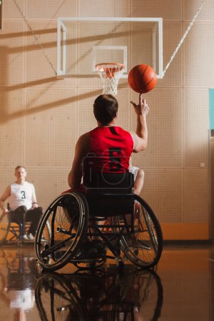 Téléchargez les photos : Jeu de basketball en fauteuil roulant : Joueur qui tourne la balle sur son doigt. Compétence d'une personne handicapée gagnante. Vue arrière prise - en image libre de droit