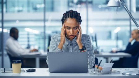 Photo for Young Black Woman Office Worker Uses Laptop, Feels Sudden Burst of Pain, Headache, Migraine. Overworked Accountant Feeling Project Pressure, Stress - Royalty Free Image