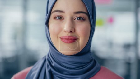 Téléchargez les photos : Décryptages Portrait d'une femme d'affaires musulmane portant le hijab regarde la caméra et sourit. Belle femme portant un foulard traditionnel. Succès - en image libre de droit