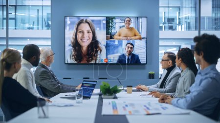 Videollamada en la sala de juntas de la oficina: Directores ejecutivos conversan con un grupo de empresarios multiétnicos, gerentes, inversores