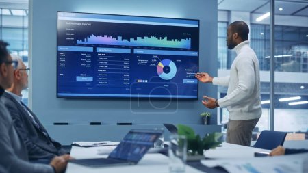 Diverse Modern Office: Motivated Black Businessman Leads Business Meeting with Managers, Talks, uses Presentation TV with Statistics, Charts, Big Data