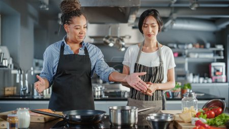 Photo for Celebrity TV Cooking Show Kitchen: Asian and Black Female Chefs Talk, Teach How to Cook Food. Online Video Courses, Television Program Presenters - Royalty Free Image