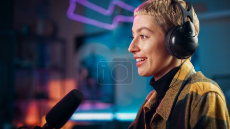 Attractive Young Female Talking Into Microphone While Recording Radio Show from Her Loft Apartment. Happy Woman with Short Hair Talking on Camera and