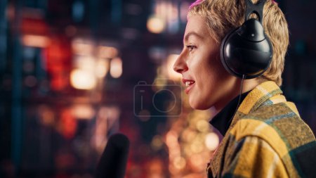 Beautiful Young Female Talking Into Microphone While Recording Radio Show from Her Loft Apartment. Happy Woman with Short Hair Talking on Camera and