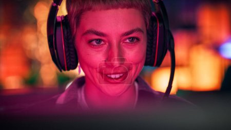 Foto de Primer plano Retrato de una mujer joven con estilo con el pelo corto jugando videojuego de ordenador en línea en la noche en casa. Jugador Discutiendo Tácticas con - Imagen libre de derechos
