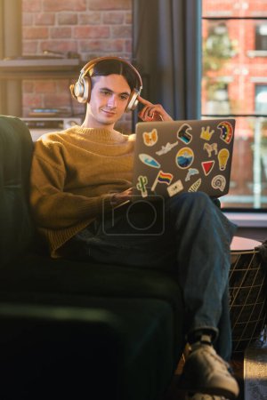 Foto de Pantalla vertical: Joven hombre guapo que trabaja desde casa en el ordenador portátil en el elegante apartamento Loft durante el día. Comprobación de personas creativas Social - Imagen libre de derechos