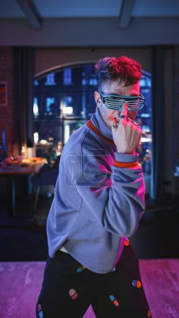 Vertical Screen: Portrait of a Handsome Young Man Dancing in Stylish Futuristic Neon Glowing Glasses, Having a Party at Home in Loft Apartment
