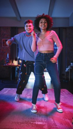 Vertical Screen: Diverse Multiethnic Couple in Cozy Clothes Recording a Dance Video from an Evening Party at Home in Loft Apartment. Performing for