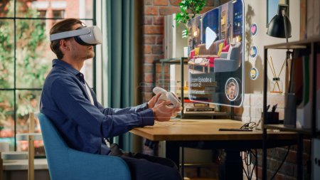 Jeune homme assis dans le salon Loft à la maison, en utilisant un casque de réalité virtuelle avec des contrôleurs pour utiliser l'application de streaming de divertissement cinématographique. Hommes