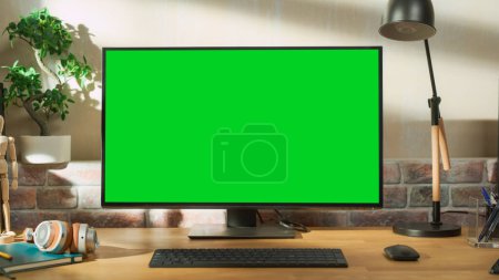 Foto de Escritorio Personal Computer Monitor De pie sobre una mesa con una pantalla verde Chromakey Mock Up Display. Acogedor apartamento Loft vacío con una lámpara, Cuadernos - Imagen libre de derechos