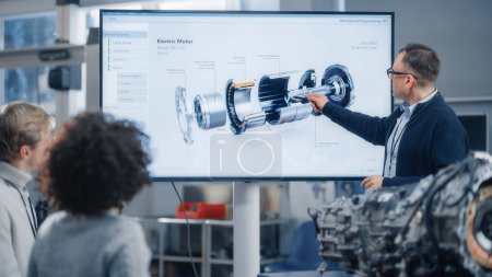 Photo for Professor Lectures Diverse Group of Multi Ethnic Students and Pointing at Model of Turbine Engine on Big Television Screen in University. Engineering - Royalty Free Image