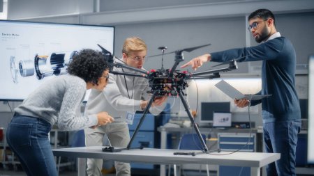 Photo for Young Specialists Connecting Drone to a Laptop. Engineers Try to Make Jobs Safer, Easier and More Efficient by Automated Contactless Delivery Machines - Royalty Free Image