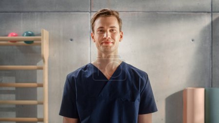 Foto de Portrait of a Handsome Professional Male Nurse in Uniform Standing and Posing for Camera, Smiling in Medical Rehabilitation Center. Physiotherapy - Imagen libre de derechos