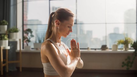 Téléchargez les photos : Young Beautiful Female Exercising, Practising Meditation in the Morning in Her Bright Sunny Loft Apartment. Healthy Lifestyle, Fitness, Wellbeing and - en image libre de droit
