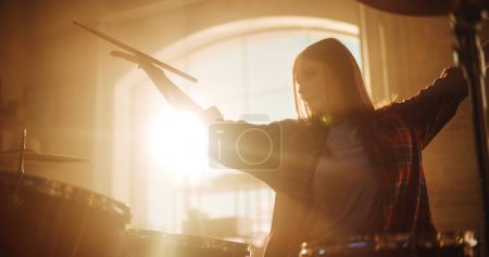 Téléchargez les photos : Close Up Portrait of an Expressive Drummer Girl Playing Drums in a Loft Music Rehearsal Studio Filled with Light. Rock Band Music Artist Learning a - en image libre de droit