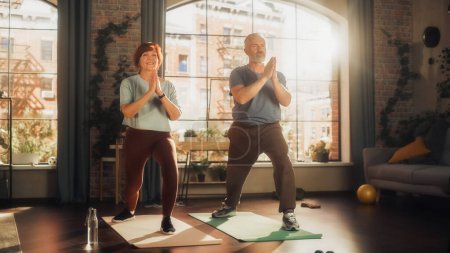 Photo for Happy Smiling Senior Couple Doing Gymnastics and Yoga Stretching Exercises Together at Home on Sunny Morning. Concept of Healthy Lifestyle, Fitness - Royalty Free Image