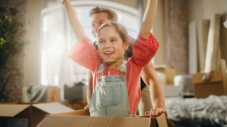 Moving in: Young Family of New Homeowners Has Fun. Father Driving Lovely Little Daughter in Cardboard Box. Cheerful Dad and Girl Racing Together