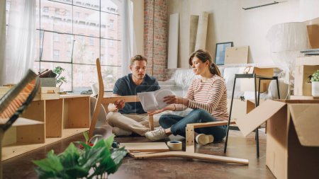 Téléchargez les photos : Family Moving in and Home Renovations: Happy Couple Assembles Furniture as a Team, Girlfriend Reads Instructions and Boyfriend Follows them with some - en image libre de droit