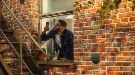 Verzweifelter junger schwarzer Mann versteht nicht, warum es keine Mobilfunkverbindung auf seinem Smartphone gibt und greift hektisch mit dem Handy in den Himmel