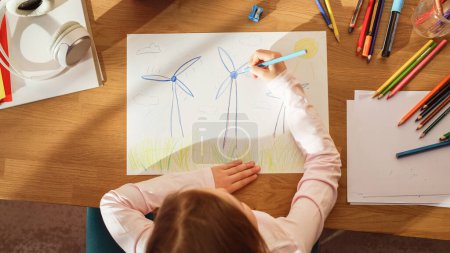 Vue du dessus : Petite fille dessinant de belles éoliennes qui ressemblent à des fleurs. Le jour ensoleillé Smart Talented Child Imaginer notre planète comme un endroit heureux