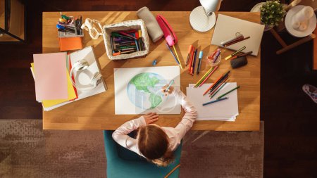 Téléchargez les photos : Vue du dessus : Petite fille dessinant notre belle planète Terre. Enfant très talentueux s'amuser à la maison, Imaginer notre planète à la maison comme un endroit heureux avec - en image libre de droit