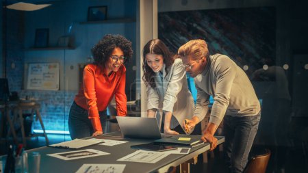 Photo for Diverse Team of Young Managers Discussing Work at a Meeting in Office at Night. Successful Business Partners Talking About a Marketing Campaign - Royalty Free Image
