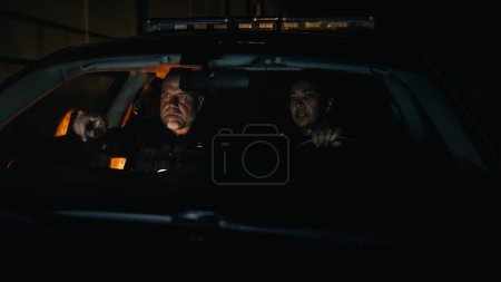 Foto de Punto de vista: Dos oficiales de policía en servicio que conducen el coche de la patrulla de tráfico, reciben la llamada del escáner de emergencia del centro despachador, responden, encienden las sirenas - Imagen libre de derechos