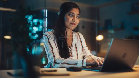 Photo for Portrait of a Happy Indian Manager Working in Creative Office. Business-Driven Stylish Female with Long Dark Hair Using Laptop Computer for Making - Royalty Free Image