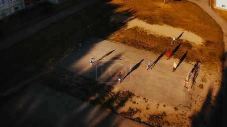 Luftaufnahme talentierter multiethnischer Kinder, die an einem sonnigen Sommertag in ihrem Hinterhof Fußball spielen. Sportliche Jungen und Mädchen genießen ein Spiel